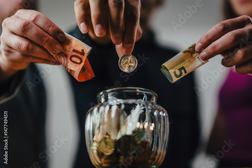 Drei Personen zahlen gemeinsam in ein Glas ein