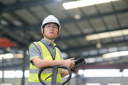 An Asian male worker  forklift  while holding digital tablet photo