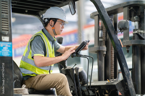 An Asian male worker is driving a forklift photo