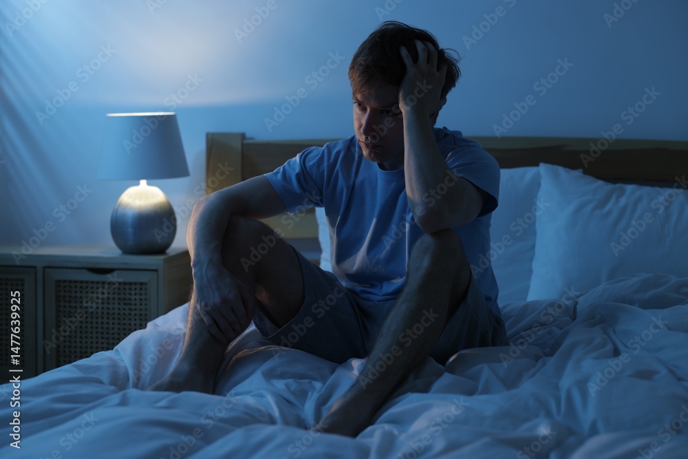 Fototapeta premium Frustrated man suffering from insomnia on bed indoors