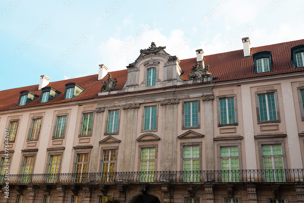 Fototapeta premium Elegant baroque-style building with a red-tiled roof and decorative stone facade in Warsaw’s historic center. A cultural heritage site perfect for travel, European cityscapes, and architectural