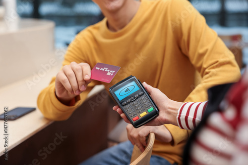 Payment terminal with NFC system. Client using credit card to pay for service indoors, closeup