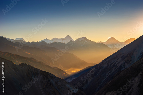 Himalaya mountains at sunrise. Himlung and Manaslu summits behind Pisang peak illuminated by first rays of the sun. View from the trekking route to Tilicho lake.