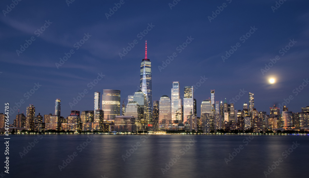 Fototapeta premium new york city skyline view during blue hour just after sunset (dusk nightfall night time photography from jersey city waterfront) hudson river downtown skyscrapers tall commercial buildings reflecting