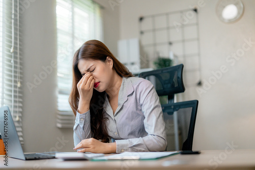 Fatigued businesswoman massaging temples, experiencing visual strain from prolonged screen time