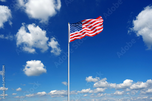 flag of The United States fluttering in the blue sky with cumulus clouds