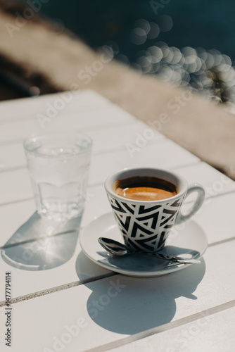 Cup of black coffee and a glass of water on a table in a street cafe in a sunny morning.