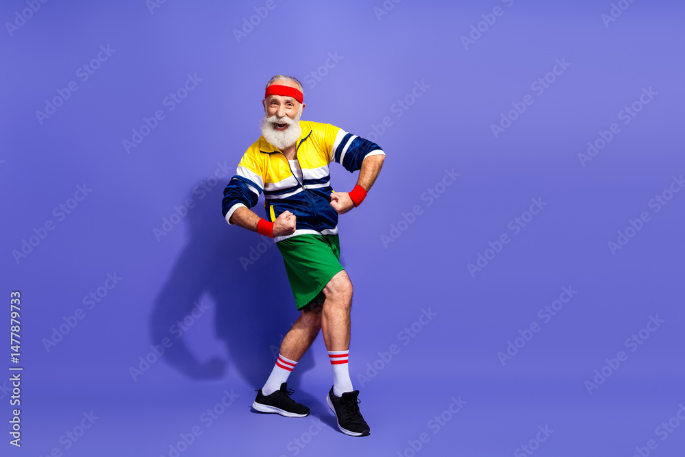 Naklejka premium Energetic senior man in retro sportswear striking a funny pose on a vibrant background showing lively spirit and vitality