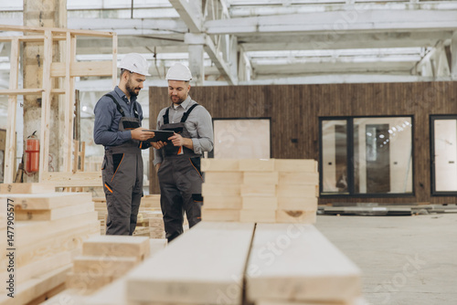 Construction workers using digital tablet in modular building factory