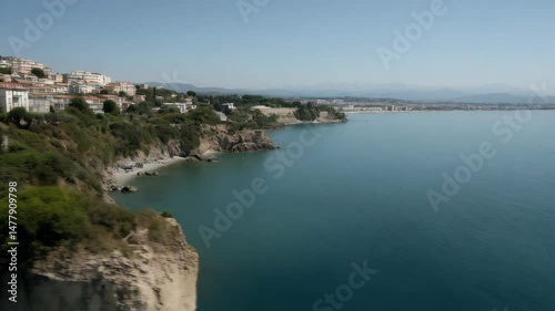 Wallpaper Mural Aerial shot of houses and buildings on a cliff overlooking a blue ocean and distant coastal city skyline under a clear sky. Torontodigital.ca