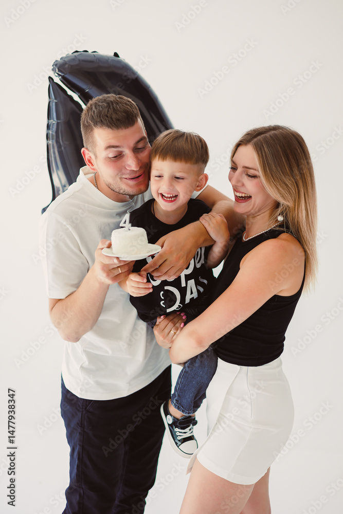 Happy young family dad, mom and boy around birthday cake. Celebrating children's birthday in family circle.