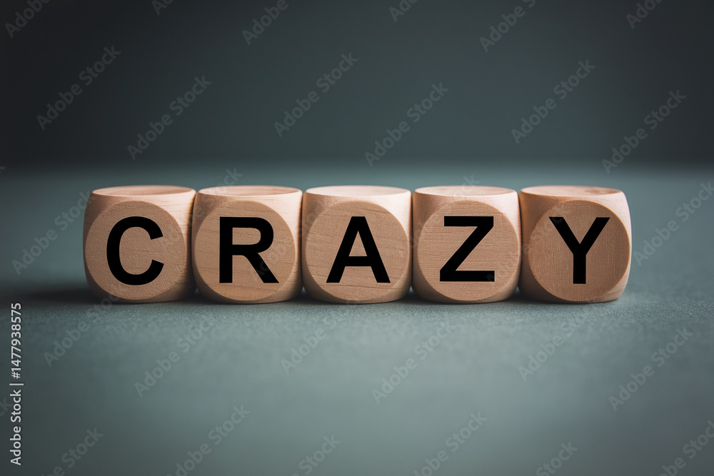 Obraz premium Wooden cubes spelling word crazy on dark background, showcasing a concept of unpredictability or excitement