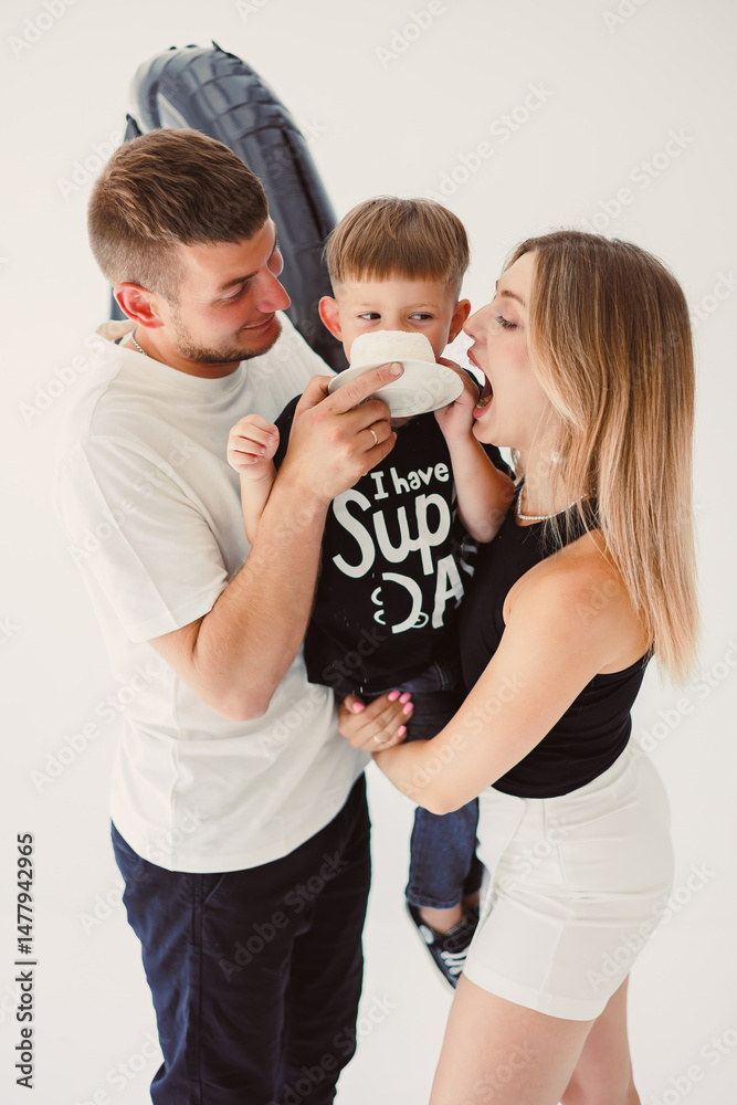 Mom, dad and son celebrate their son's birthday. 4 year old boy eats sweet birthday cake.