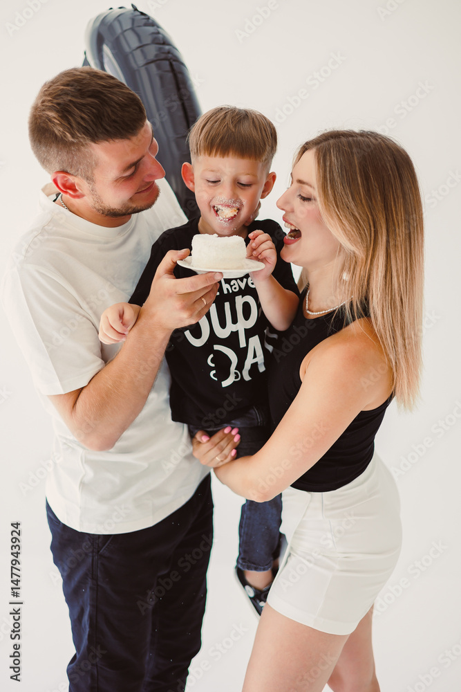 Mom, dad and son celebrate their son's birthday. 4 year old boy eats sweet birthday cake.