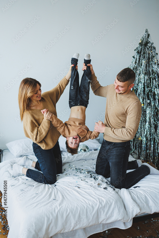 A joyful moment is captured between loving parents and their child on a cozy bed, surrounded by charming holiday decorations, enhancing the warmth and comfort and creating lasting memories