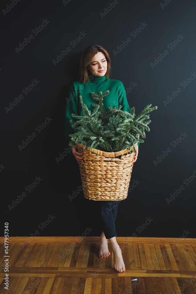 An elegant woman is gracefully holding a beautifully arranged basket filled with lush greenery, set against a dark and moody background that adds depth to the composition, enhancing its visual allure