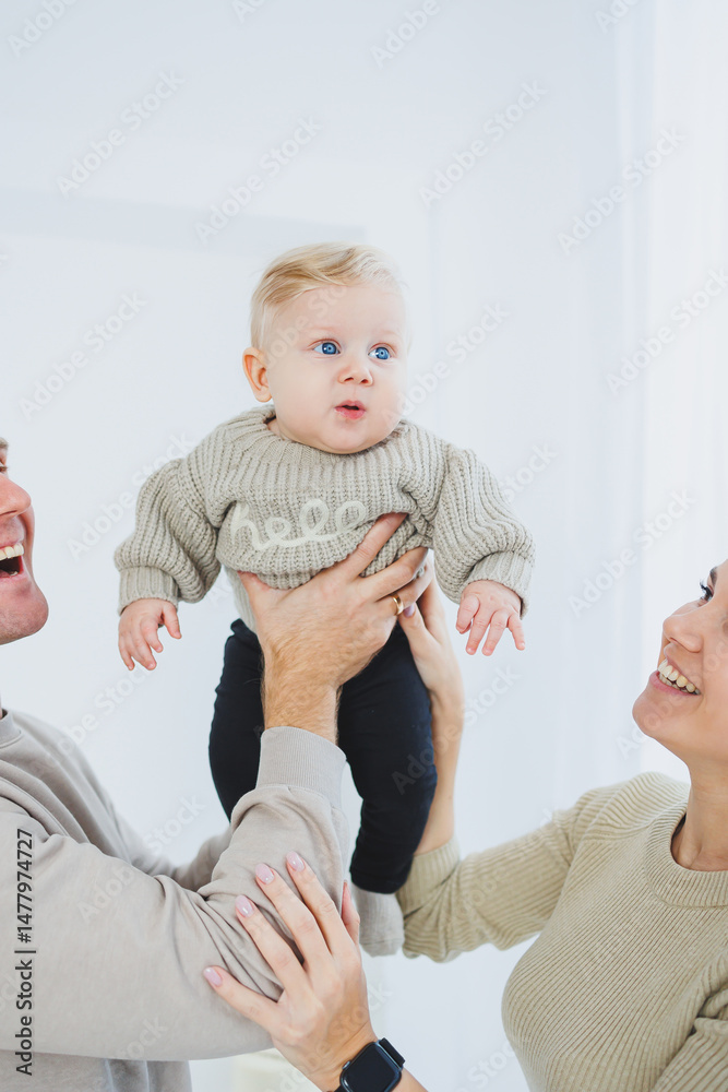 Joyful Family Moments Parents Playfully Lifting Their Adorable Baby in Their Bright, Modern Home Filled with Laughter and Love, Creating Cherished Memories Together through Wholesome Interactions