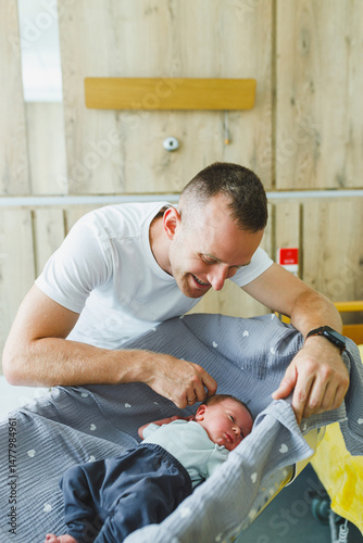 Obraz na płótnie A heartwarming moment unfolds as a devoted father and his newborn baby create an incredible bond in the hospital nursery, filled with love and joy, making cherished memories that last a lifetime w salonie
