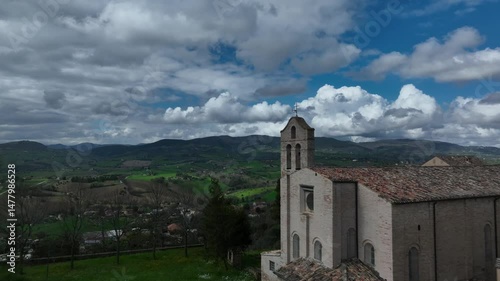 Drone glides above the rooftops of historic Treia, showcasing the ancient temple and a breathtaking natural landscape in the background. photo