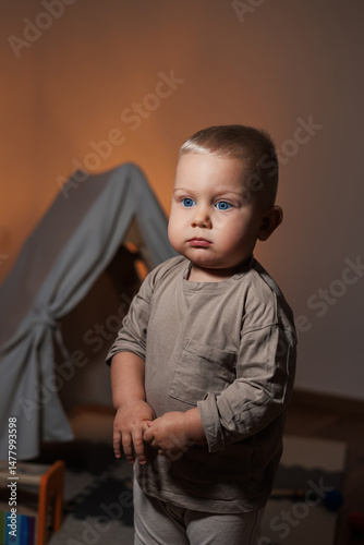 Obraz na płótnie In a bright and colorful room filled with warm lighting, a cheerful young child stands happily, embodying a cozy atmosphere that is perfect for exploration and creating joyful moments of childhood w salonie