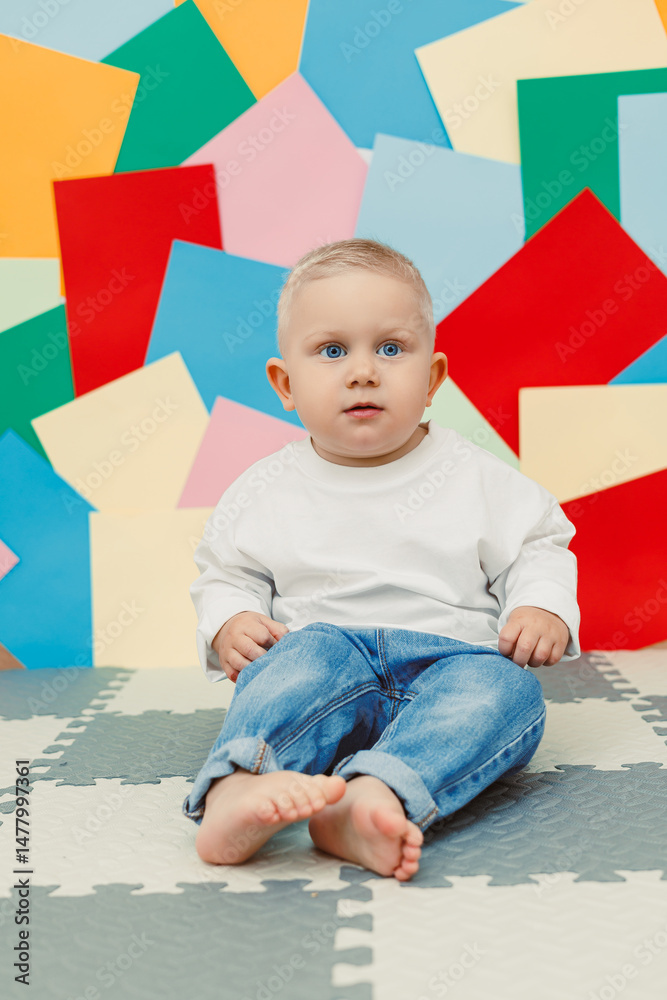 An absolutely adorable baby is sitting on a colorful background that creates a playful environment, beautifully capturing the essence of innocence and the joyful moments that define early childhood