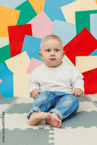 An absolutely adorable baby is sitting on a colorful background that creates a playful environment, beautifully capturing the essence of innocence and the joyful moments that define early childhood