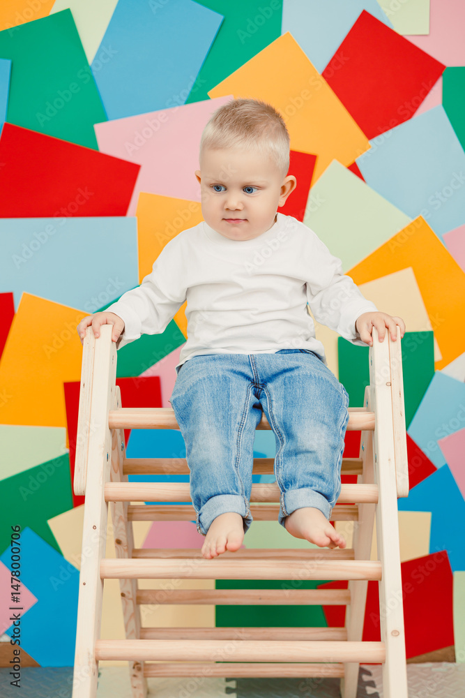 A charming and delightful child happily positioned on a wooden ladder in a vividly colorful playroom, smiling joyfully into the camera, exuding pure innocence and happiness, truly captivating