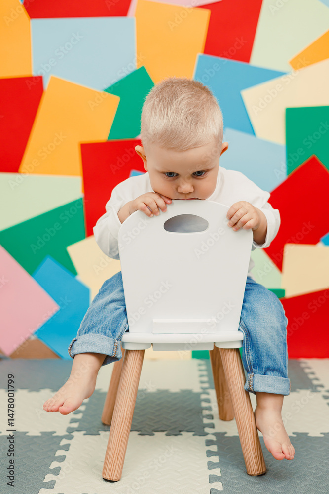 A curious toddler eagerly exploring his environment while comfortably seated on a stylish chair that stands out against a vibrant and colorful background, fostering educational and fun experiences