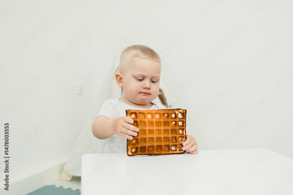 A curious and adorable toddler is examining a delicious waffle in a bright and minimalist setting, showcasing an engaging moment filled with joy, imagination, and exploration during mealtime