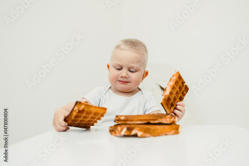 Obraz na płótnie A little child seated at the table, enjoying delicious wafflesthis captures a sweet and joyful moment in their life. Its a celebration of childhood filled with innocence and happiness w salonie