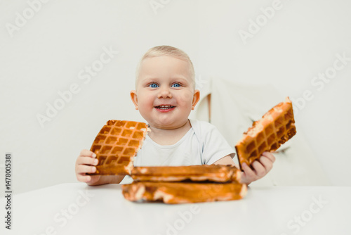 Obraz na płótnie A Joyful and Excited Toddler Relishing Every Bite of Delicious Waffles While Sitting at the Table Capturing Precious Moments of Pure Childhood Delight and Happiness, Full of Innocence and Fun w salonie
