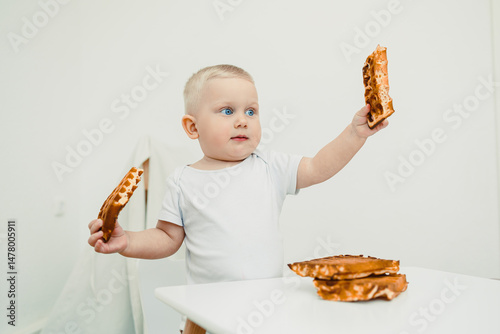 A Curious Baby is Gently Exploring Delicious Waffles in a Bright, Minimalist Kitchen Setting Filled with Light and Cheerful Colors, Creating a Perfect Environment for Fun and Playful Moments