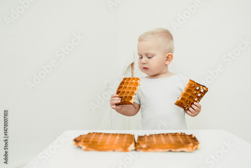 A Curious Toddler Holding Waffle Pieces This captures a delightful and fun moment filled with exploration and taste, showcasing the innocence and joy of childhood as they enjoy their tasty snacks