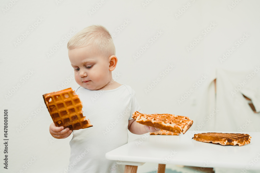 A delightful and cute child is excitedly exploring the delicious waffles in front of them, filled with curiosity and joy, all while situated in a bright and minimalist kitchen setting