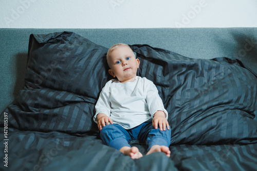 Obraz na płótnie An adorable baby is peacefully relaxing on a cozy bed that is surrounded by soft and fluffy pillows, creating a serene and comforting environment perfect for a happy and carefree time w salonie