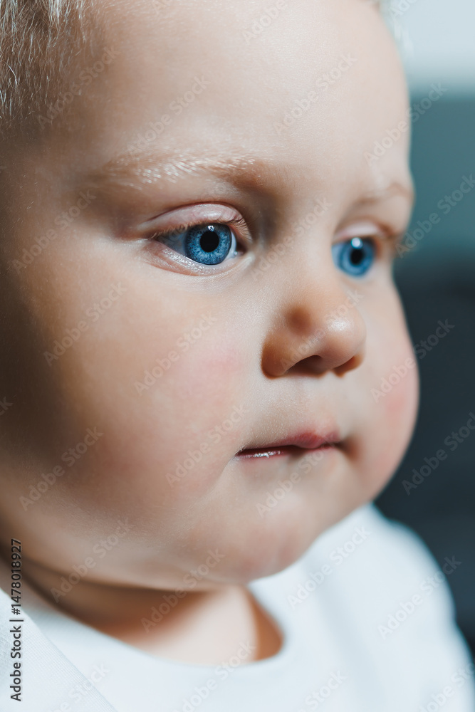 This captivating closeup portrait showcases an adorable baby with striking bright blue eyes and delicate, soft features that exude innocence, joy, and a sense of pure wonder in their expression