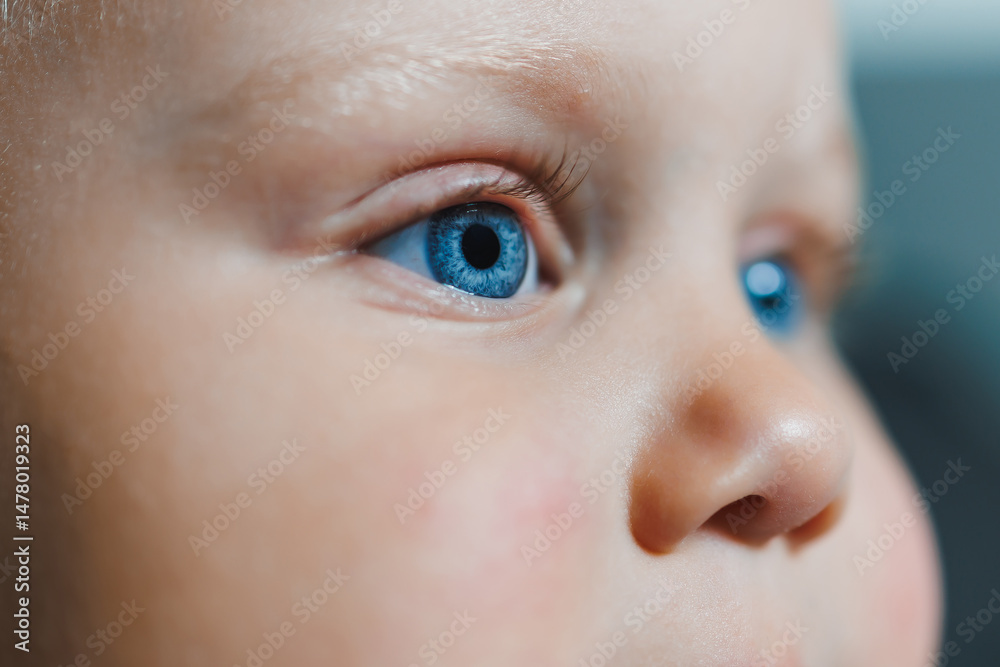 This is a closeup portrait photograph of an infants face, capturing their sparkling blue eyes and the incredibly soft and delicate textures of their skin, radiating beauty and innocence