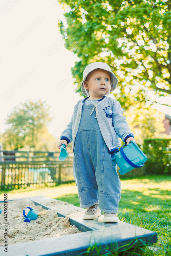 A happy toddler is joyfully playing in a spacious sandbox under the bright sunshine on a warm and cheerful sunny day, exploring and discovering the wonders of childhood and imagination