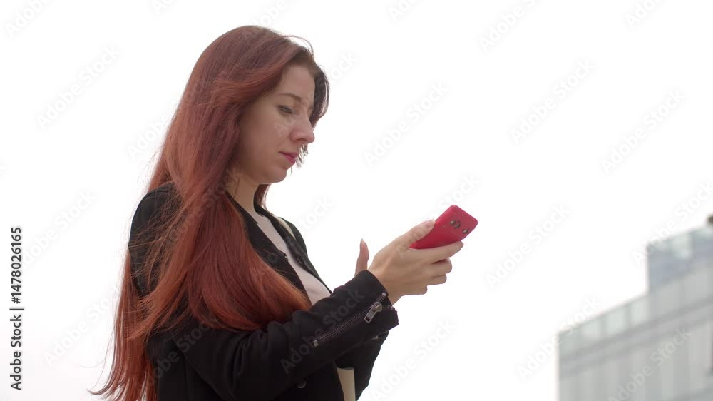 A woman talks on her cell phone while walking through the city, pausing to check her phone, capturing the blend of technology and urban life A woman talks on her cell phone while walking through the city, pausing to check her phone, capturing the blend of technology and urban life