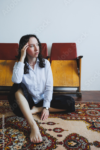 Obraz na płótnie In a serene, minimalist indoor environment, a contemplative woman sits on a beautifully colorful rug, embodying a sense of calmness while deeply engaging in her thoughts and creative pursuits w salonie