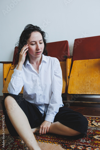 Obraz na płótnie In a serene and minimalist setting, a young woman sits on the floor while dressed in comfortable, casual clothes, fostering an environment that invites deep thought, reflection, and contemplation w salonie