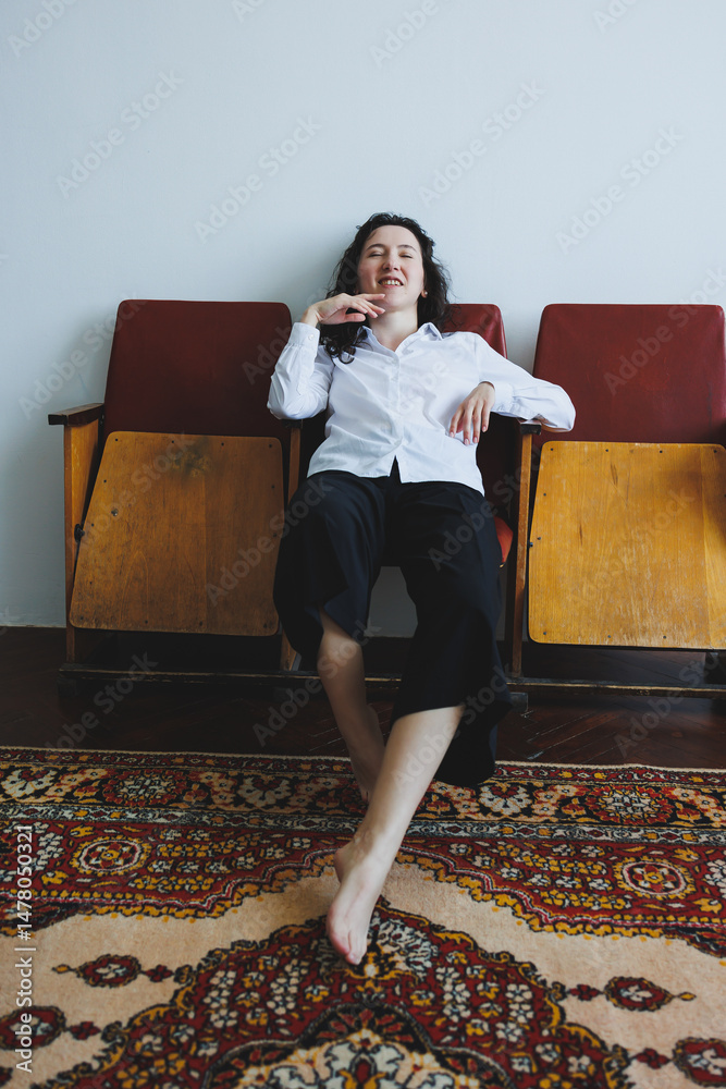 Relaxed Woman in Stylish Attire Posing Comfortably on Vintage Chairs in Cozy Indoor Setting