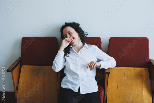 Obraz na płótnie A joyful woman relaxes on stunning vintage chairs that enhance a modern setting, creating a stylish atmosphere that invites everyone to savor the experience together, promoting connection and warmth w salonie