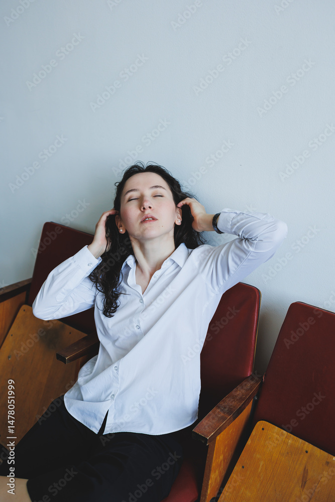 A Pensive Young Woman Dressed in Elegant Formal Attire is Calmly Relaxing on a Chair, Exhibiting a Thoughtful Expression in a Tastefully Minimalist Setting That Enhances Her Contemplative Mood