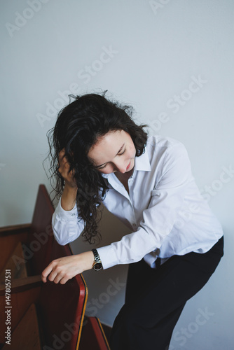 A young woman in elegant attire reflects on her life choices while sitting on a designed staircase in a serene, artistic setting, creating a moment of introspection and selfawareness