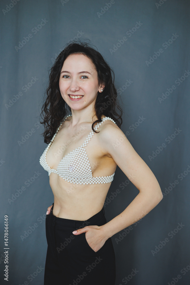 A confident young woman is elegantly posing in her stylish and trendy attire against a refreshing minimalist background that emphasizes her pose and personality, radiating beauty and grace