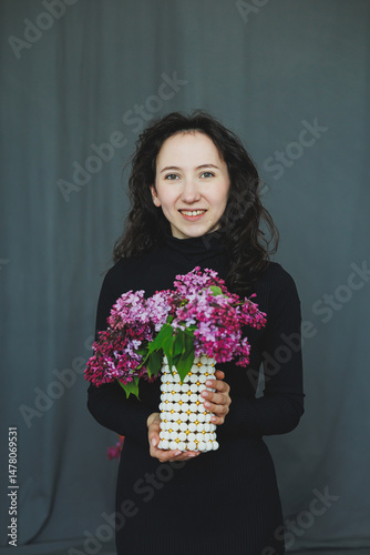 Obraz na płótnie A Cheerful Woman Holding a Beautiful Bouquet of Vibrant and Colorful Flowers in a Simplistic, Minimalist Studio Setting That Evokes a Sense of Joy and Serenity in Nature and Beauty w salonie