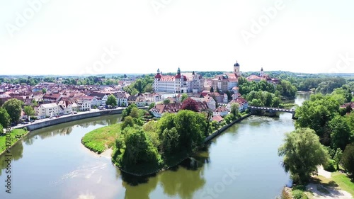 Eine beeindruckende Luftaufnahme von Neuburg an der Donau, einer malerischen Stadt in Bayern, Deutschland. Die Donau schlängelt sich durch die Stadt und bildet eine kleine Insel.