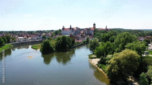 Eine beeindruckende Luftaufnahme von Neuburg an der Donau, einer malerischen Stadt in Bayern, Deutschland. Die Donau schlängelt sich durch die Stadt und bildet eine kleine Insel. photo