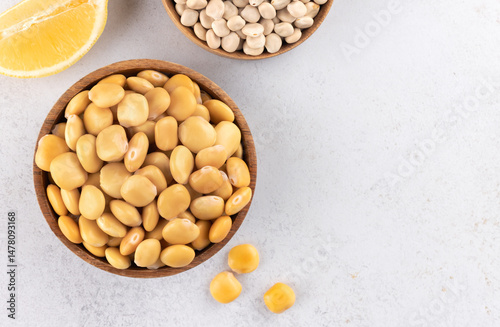 Pickled, dried lupine beans and lemon on white background. Top view. Copy space. Plant food rich in protein and fiber. photo